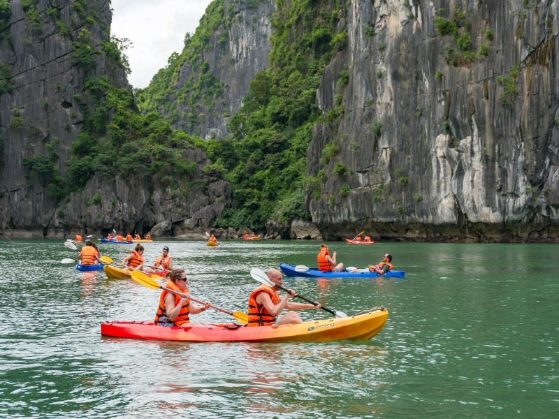Du khách đang chèo thuyền kayak qua một hang động trên Vịnh Lan Hạ